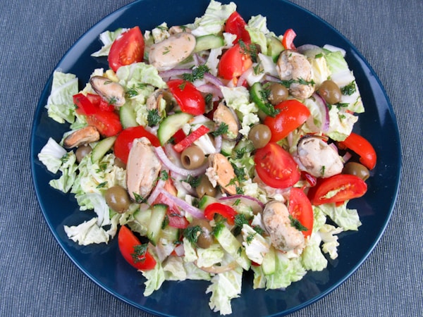 A blue plate topped with a salad covered in lots of veggies