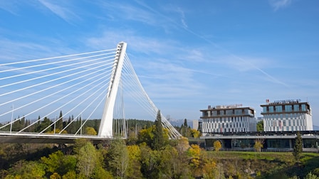 a large white bridge over a river next to a tall building