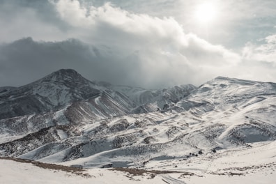 a mountain covered in snow under a cloudy sky