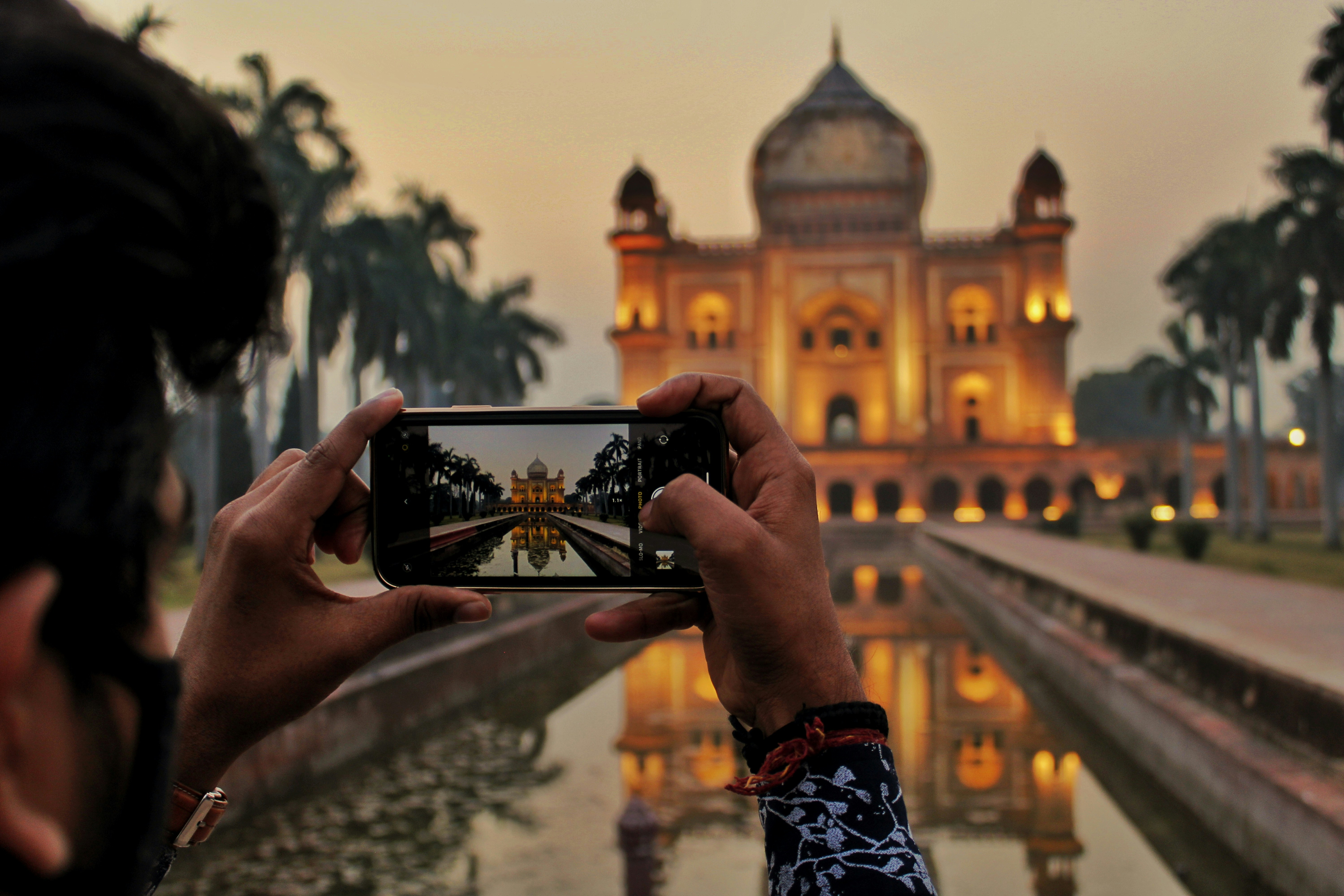 suda yansıması olan bir binanın fotoğrafını çeken kişi