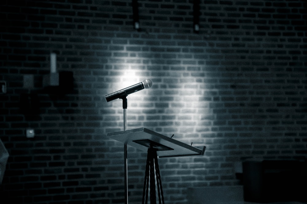 um microfone em um suporte na frente de uma parede de tijolos