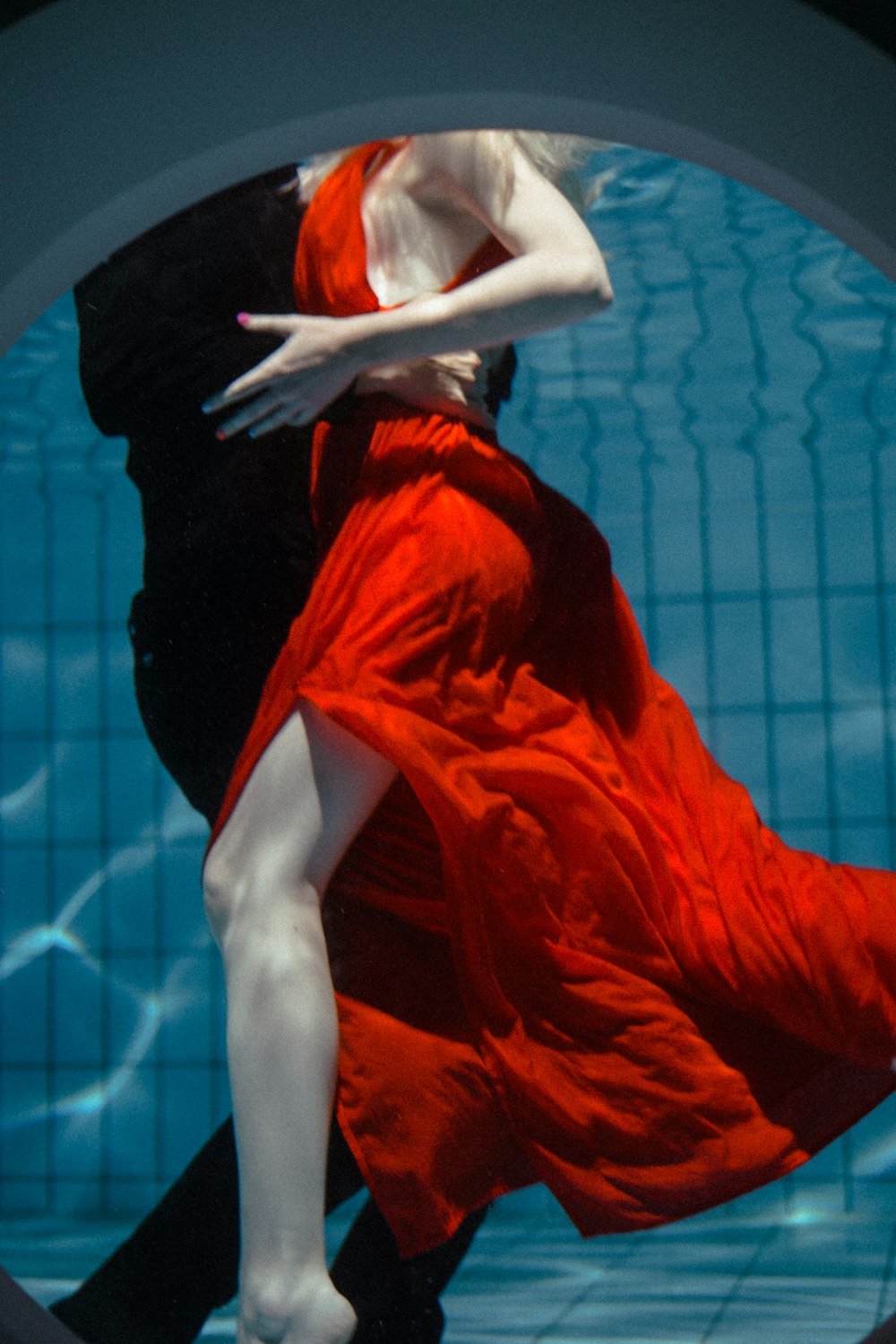 a woman in a red dress is floating in a pool