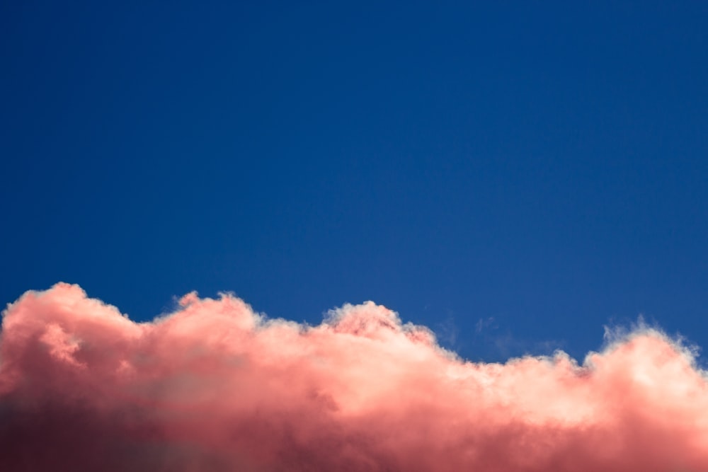 a plane flying through a blue sky with pink clouds