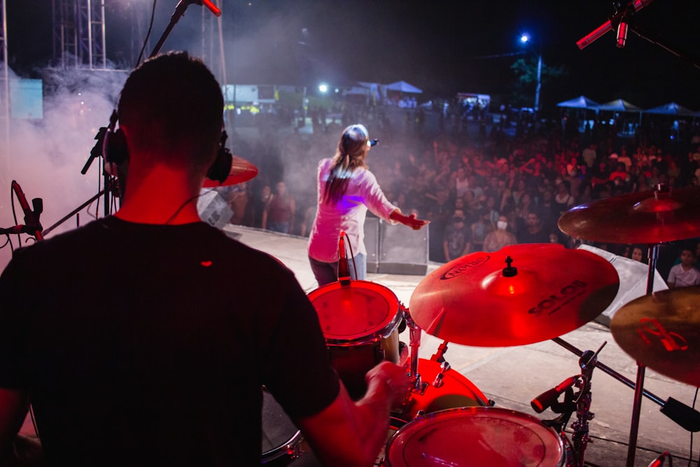 a woman standing behind a drum set in front of a crowd