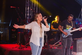 a woman singing into a microphone while standing on a stage