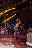 a man standing on a stage with a guitar