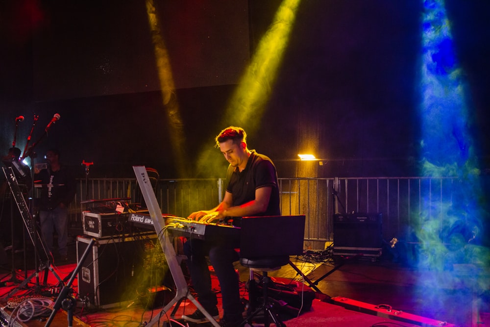 a man sitting at a keyboard on a stage