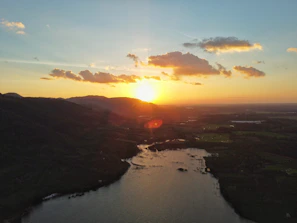 A breathtaking landscape photo of a golden sunset over rolling hills and a calm lake.