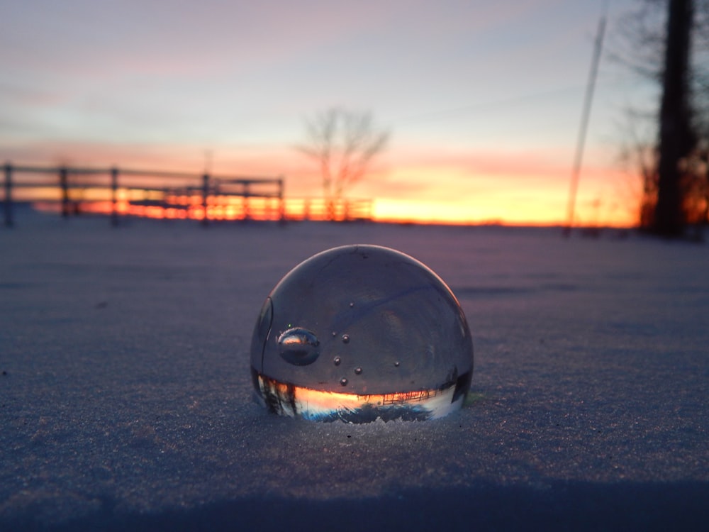 a glass ball sitting on top of a snow covered ground