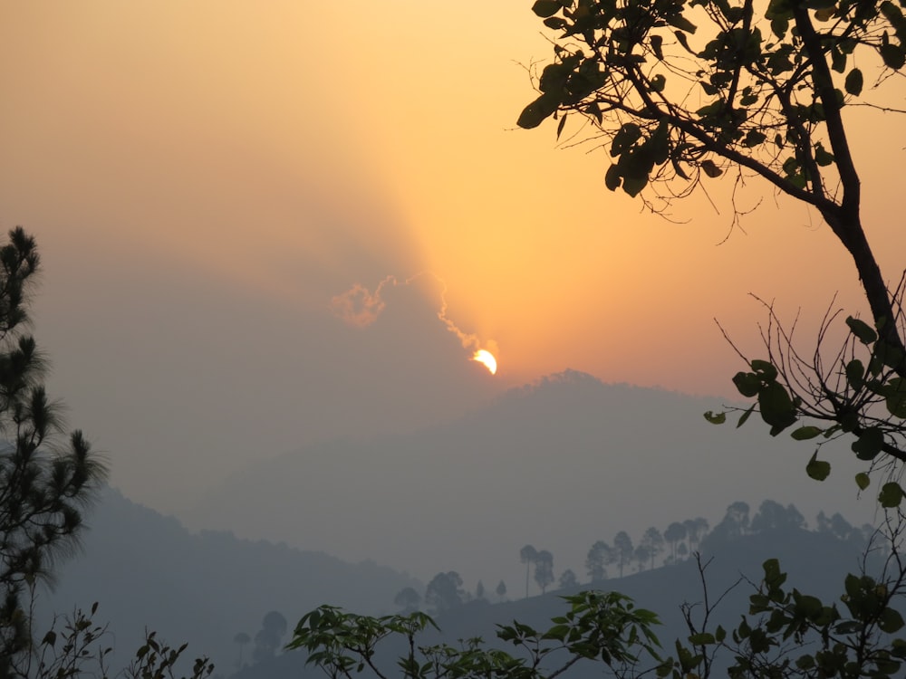 the sun is setting over a mountain range