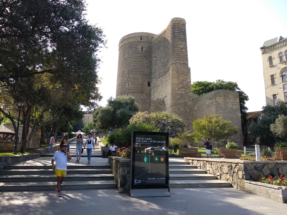 a group of people walking down a sidewalk next to a castle