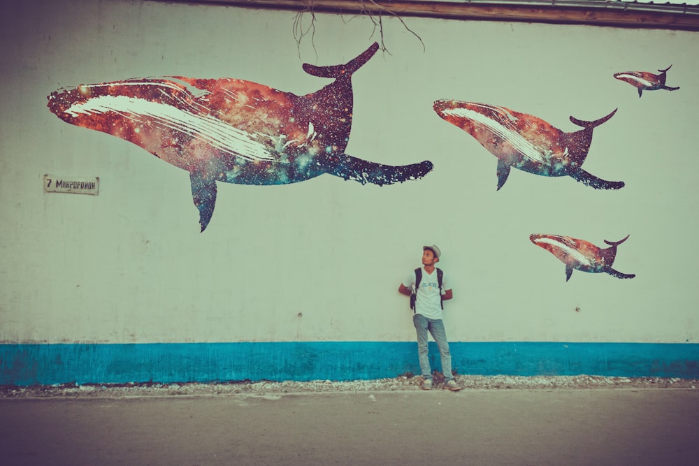 a man standing in front of a mural of dolphins