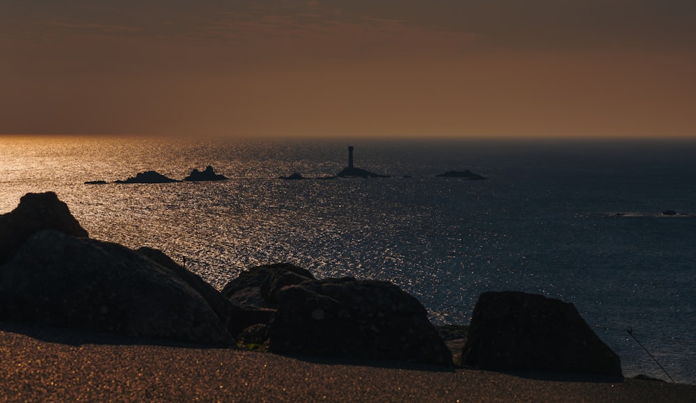 the sun is setting over the ocean and rocks