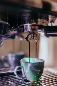 Close-up of a steaming espresso shot being poured into a small ceramic cup