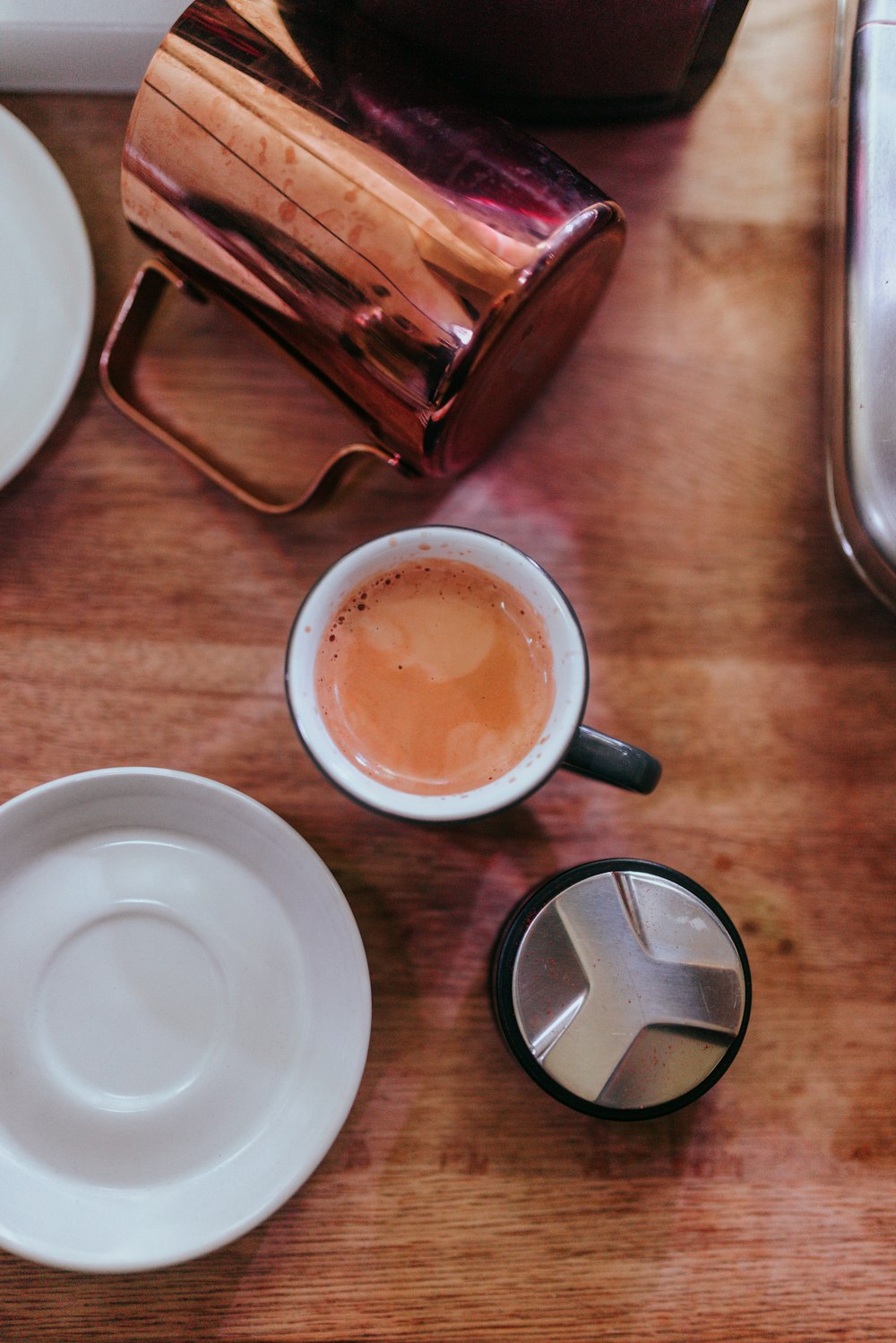 a wooden table topped with two cups of coffee