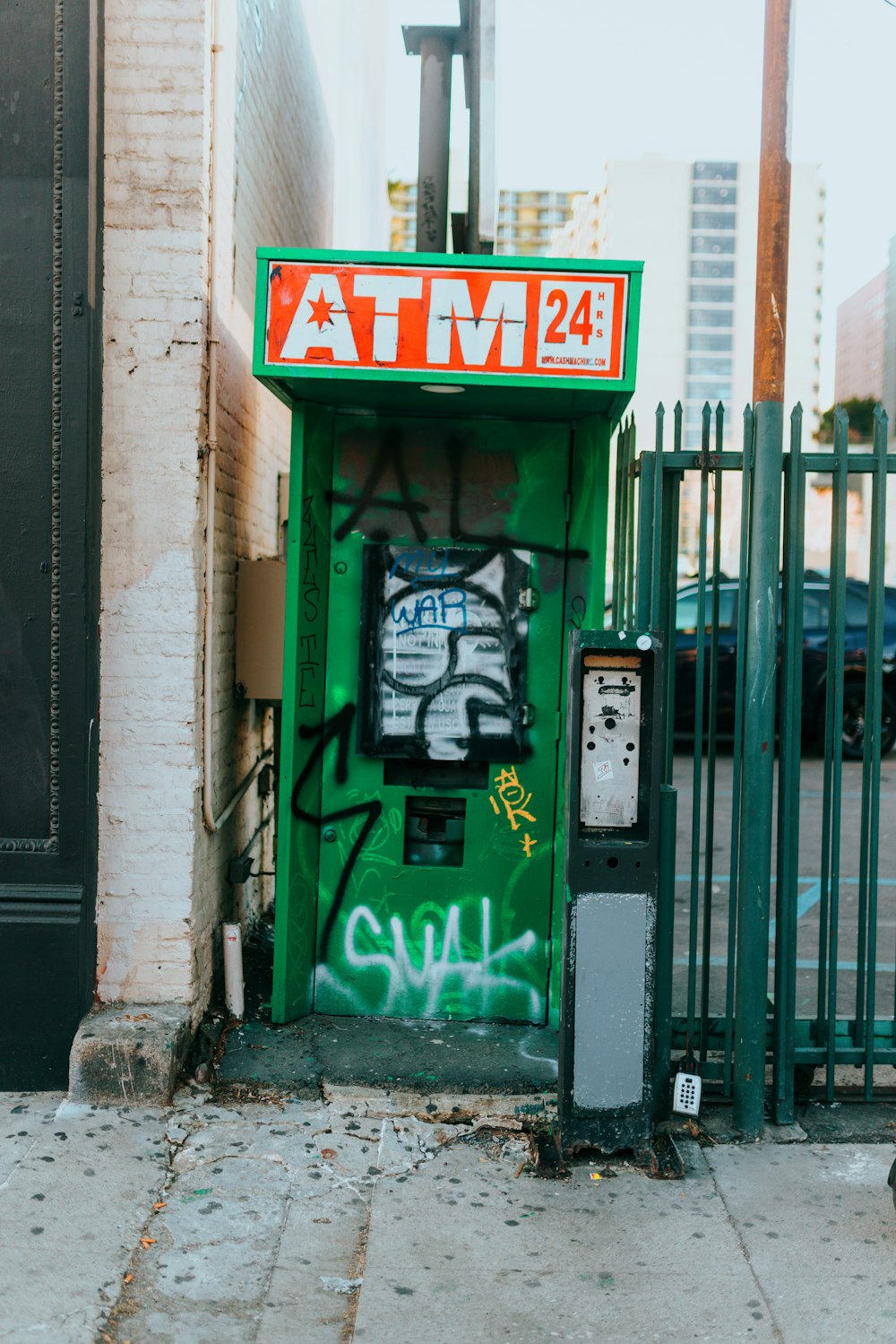 a green atm sitting on the side of a street