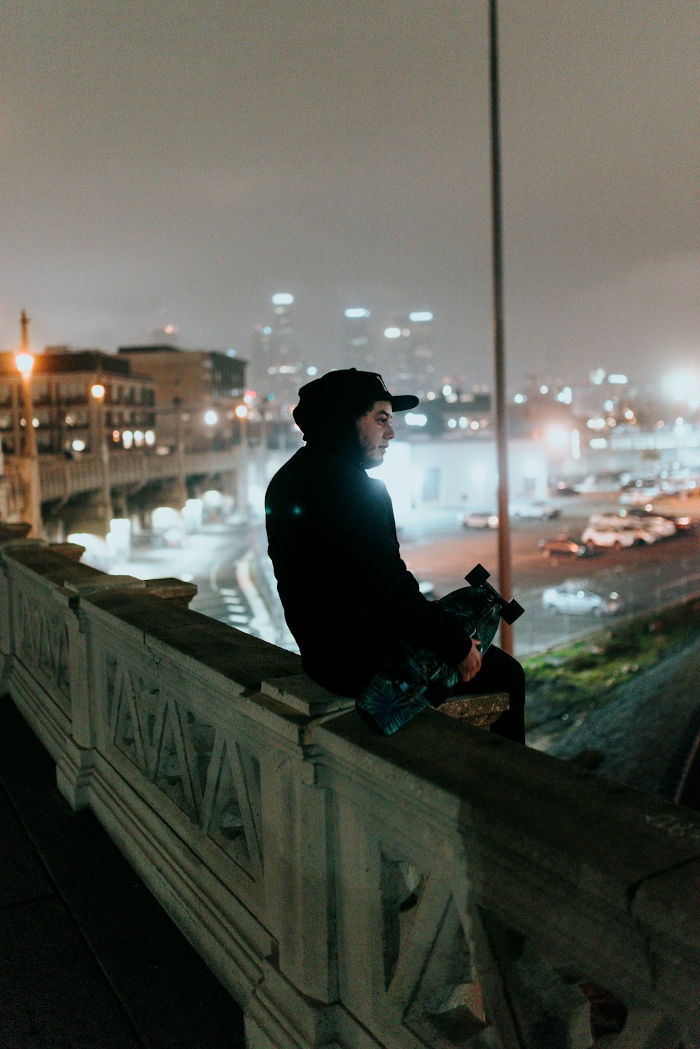 a man sitting on top of a bridge next to a tall building