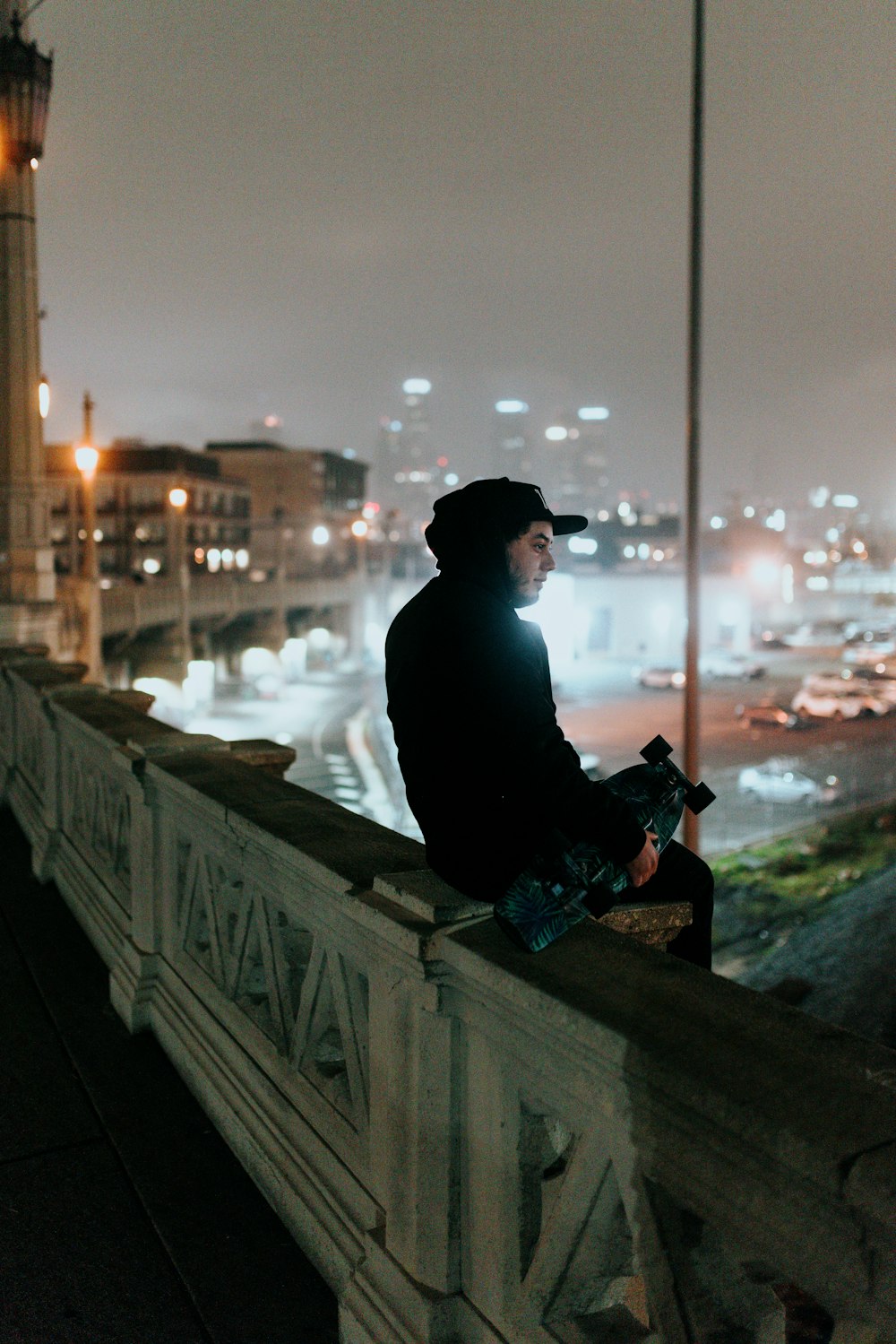 a man sitting on top of a bridge next to a tall building