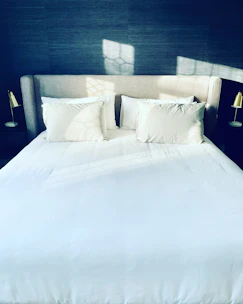 a bed with white sheets and pillows in a room
