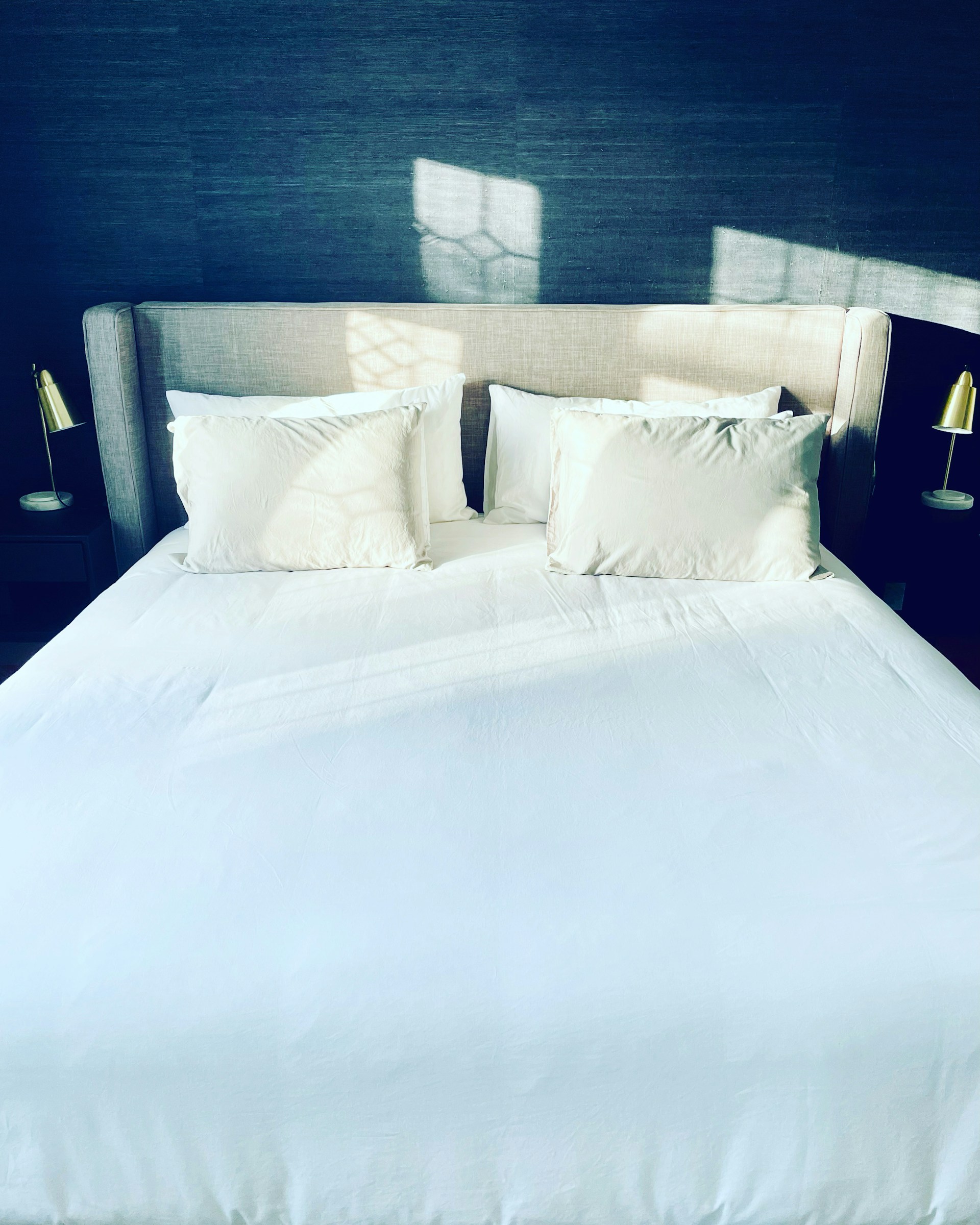 a bed with white sheets and pillows in a room