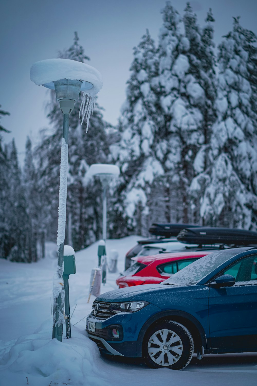 a blue car parked in a parking lot covered in snow