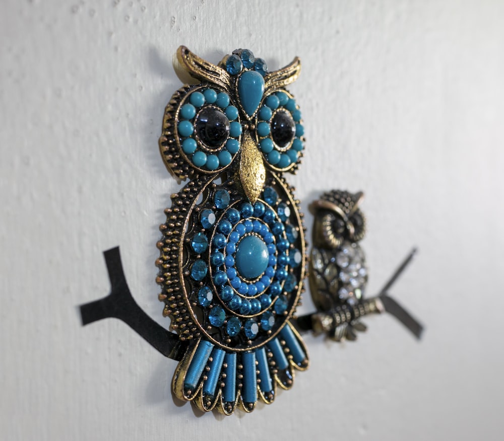 a pair of owl brooches hanging on a wall