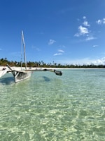 A traditional wooden boat floating on the crystal-clear waters of Raja Ampat, surrounded by lush islands