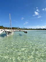 A traditional boat slicing through crystal clear waters under bright blue skies in Bali.