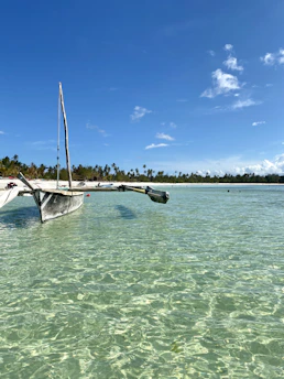 A traditional boat slicing through crystal clear waters under bright blue skies in Bali.