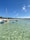 A traditional Indonesian boat sailing near lush green islands under a clear sky.