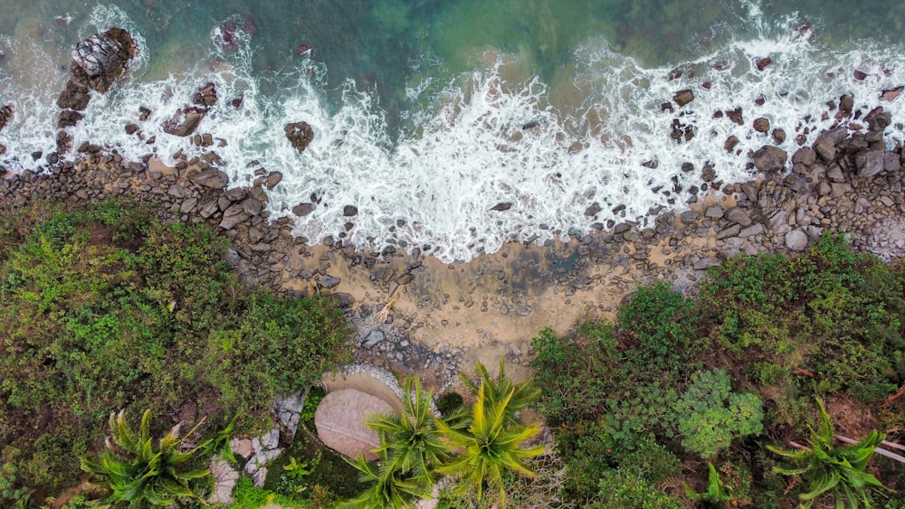 an aerial view of a beach with rocks and water