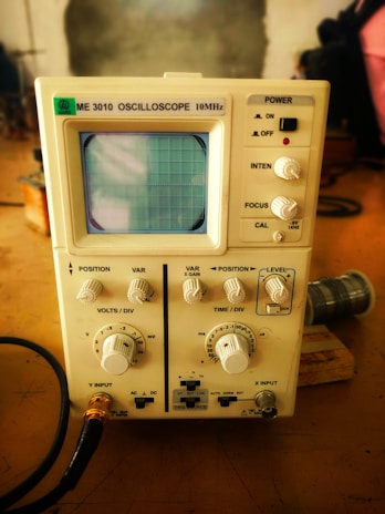 A vintage oscilloscope screen displaying colorful waveforms, surrounded by scattered electronic components.