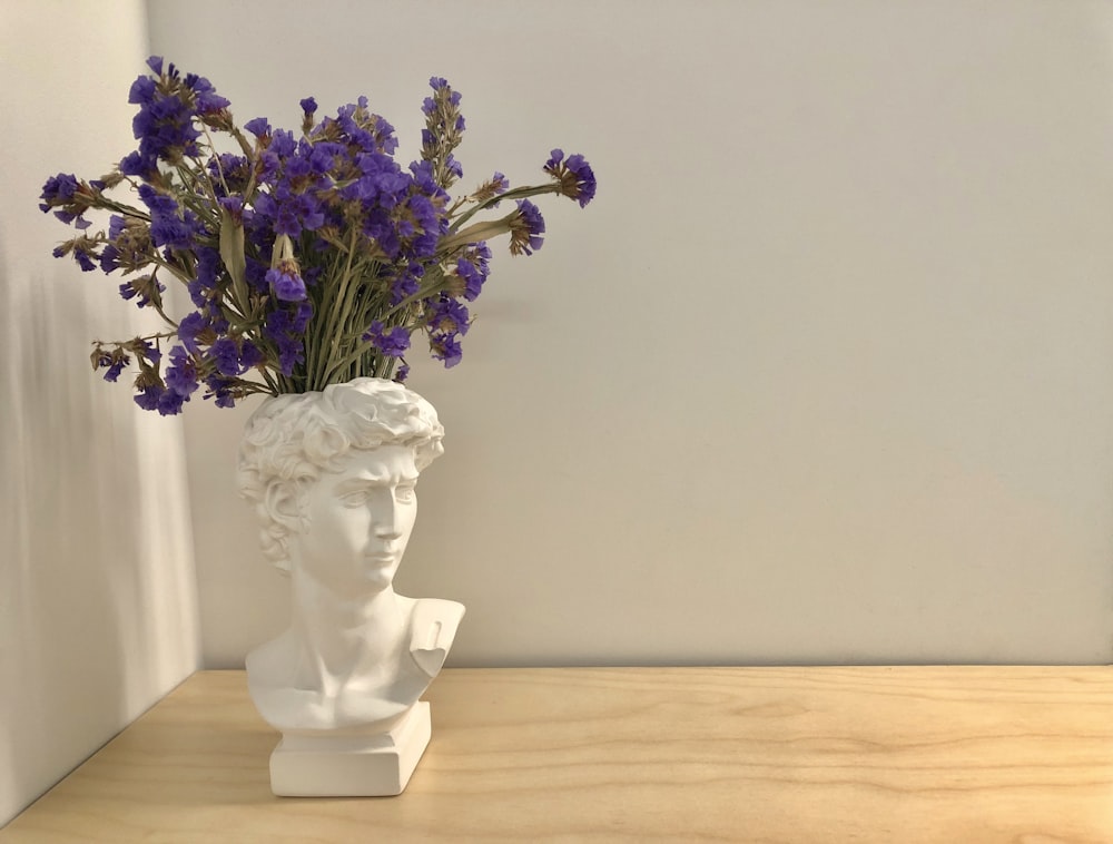 a vase with purple flowers in it sitting on a table