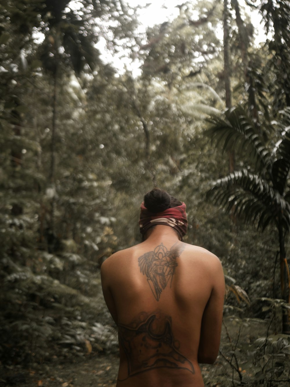 a man with a tattoo on his back in the woods