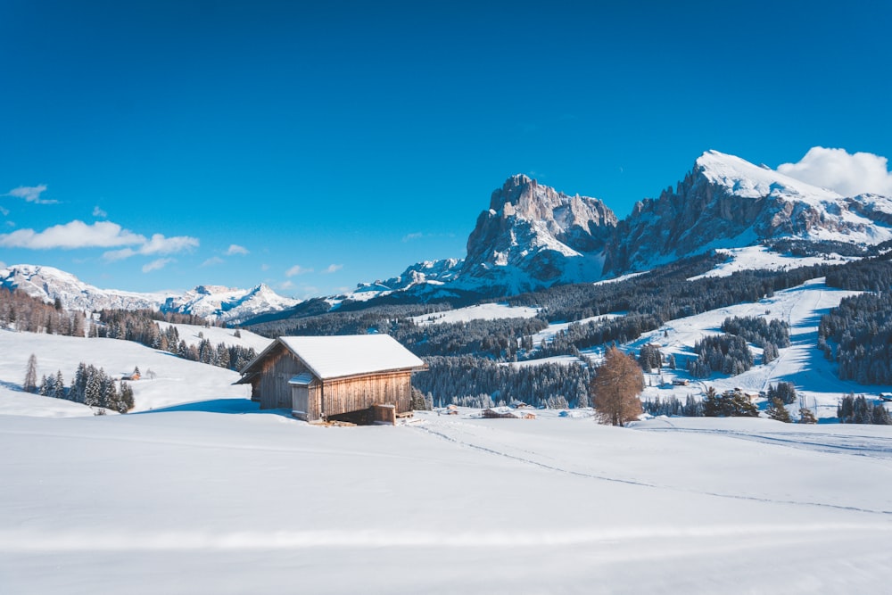 a snow covered mountain with a cabin in the foreground