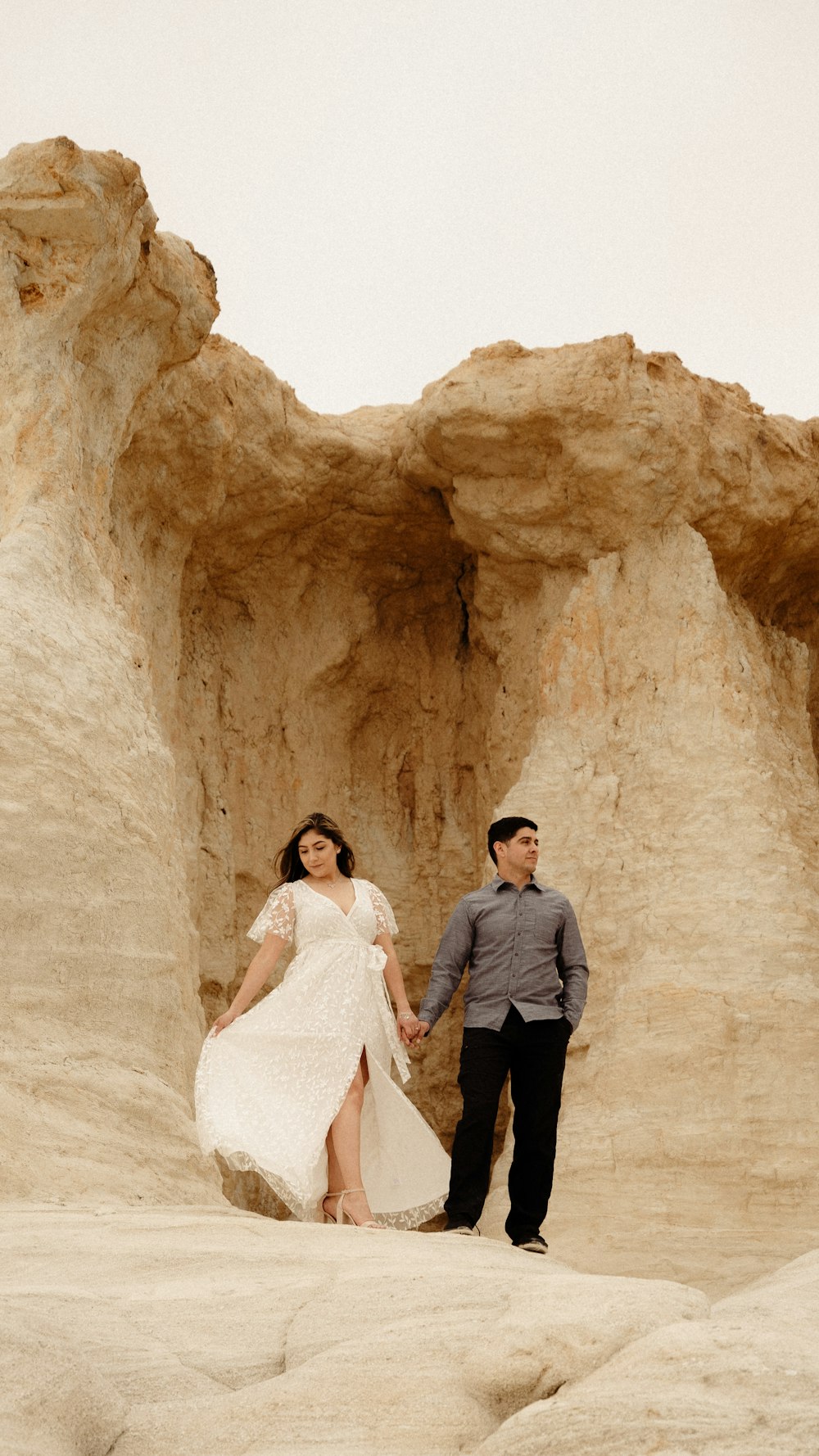 a man and a woman holding hands in the desert