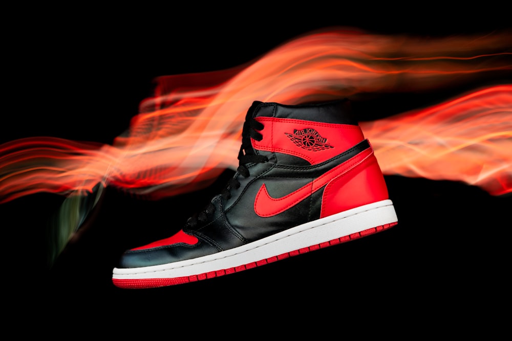 a pair of red and black sneakers with flames in the background
