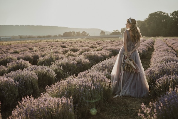 A soft-lit portrait of a woman in a flowing peach dress surrounded by blooming lavender fields.