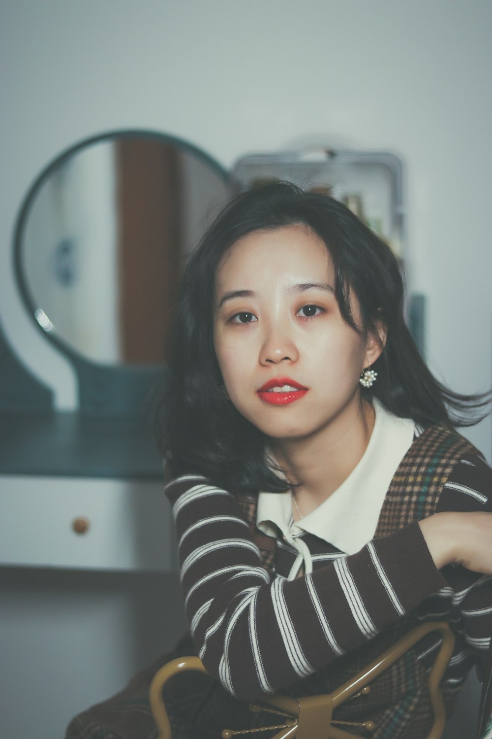 a woman sitting in front of a mirror holding a purse