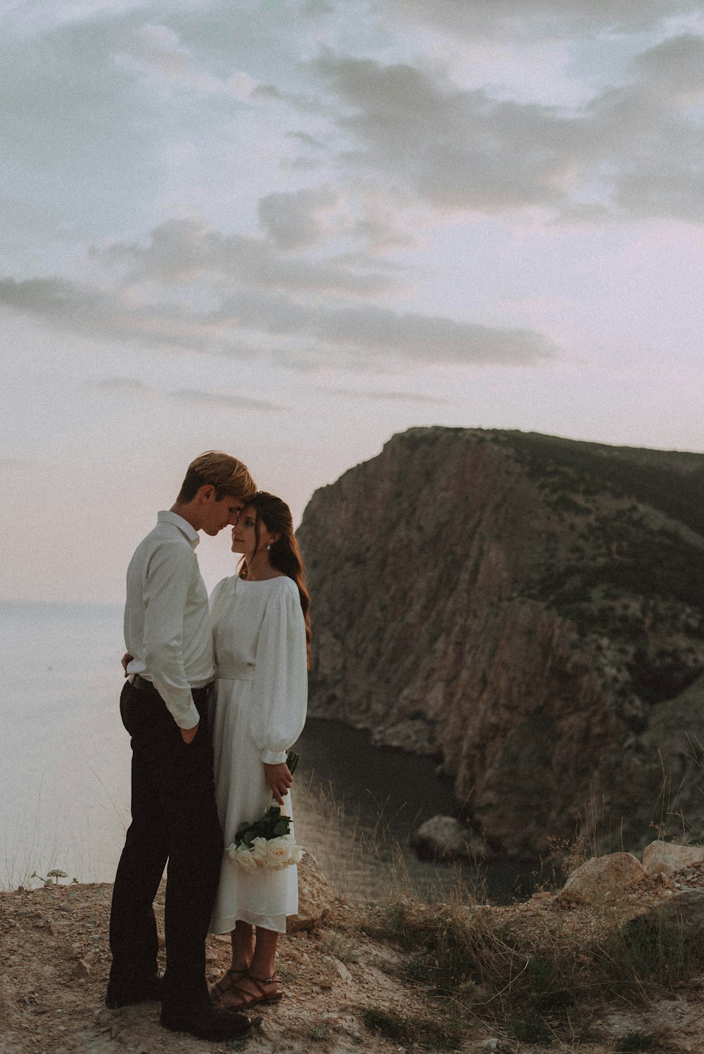 a man and a woman standing on top of a cliff