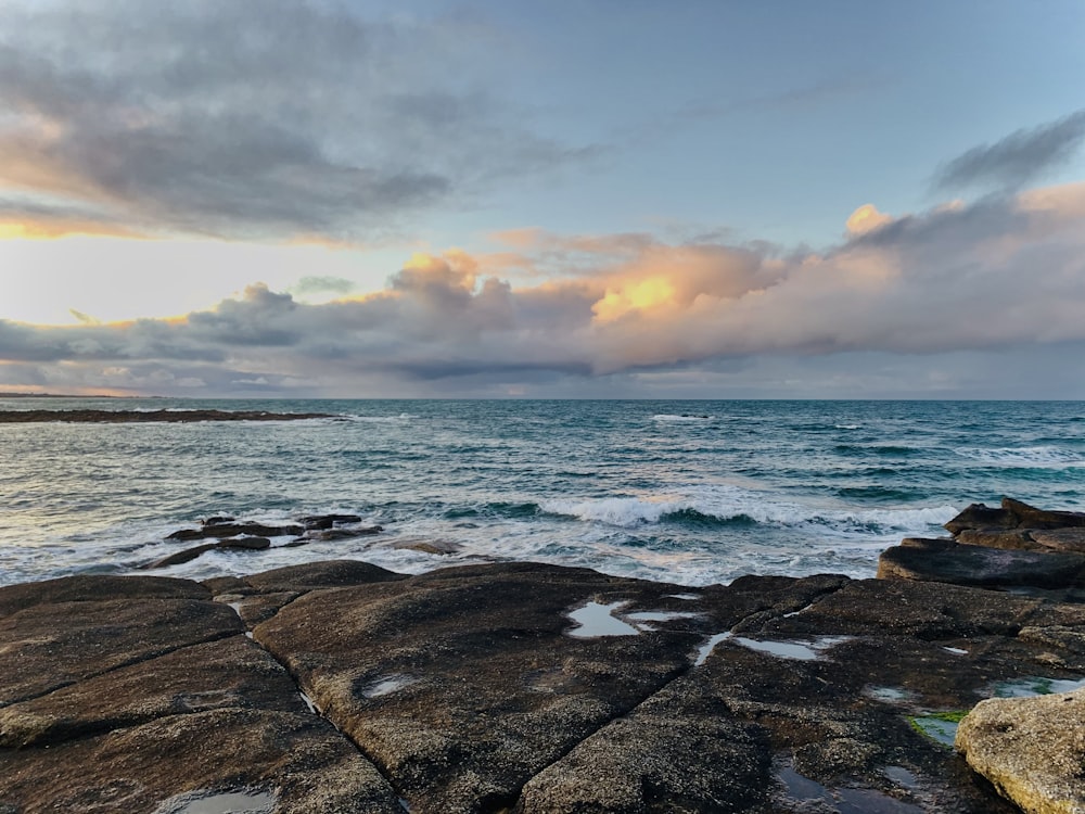 a large body of water sitting next to a rocky shore