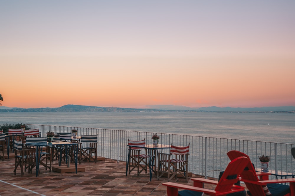 a patio with tables and chairs overlooking the ocean