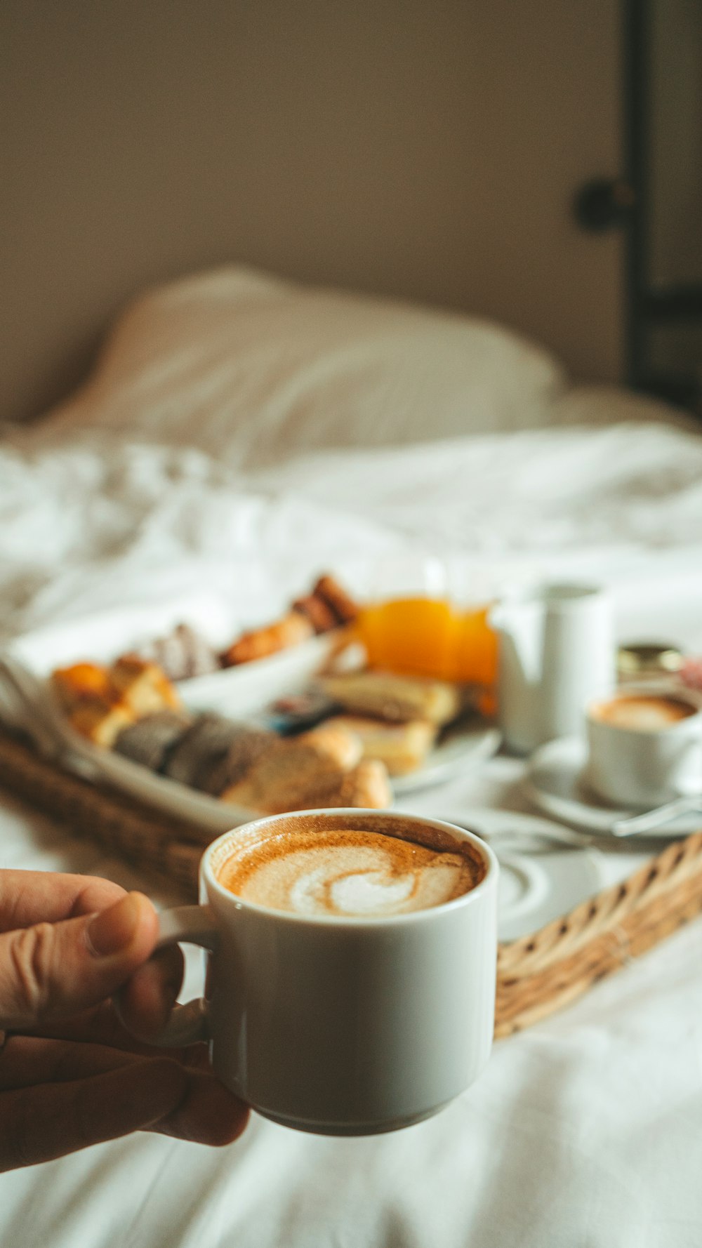a person holding a cup of coffee on a bed