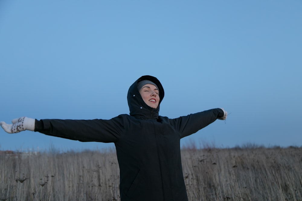 a woman standing in a field with her arms outstretched