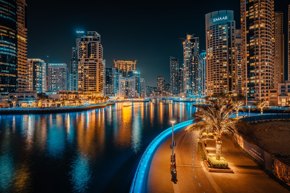 a city skyline at night with a river running through it