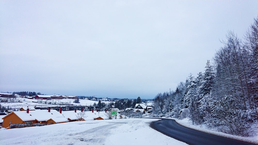 a snow covered road with houses in the background