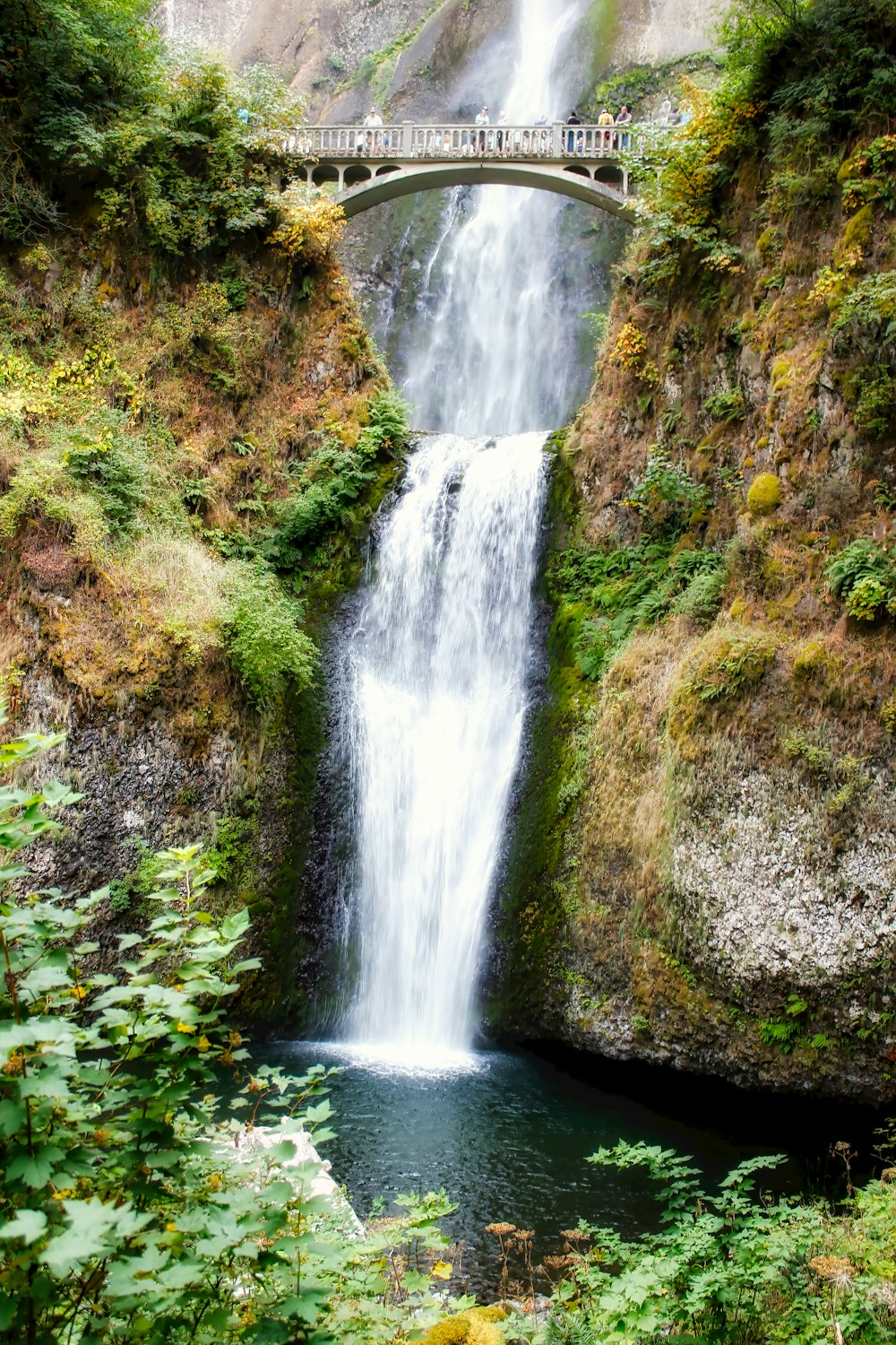 a large waterfall with a bridge over it