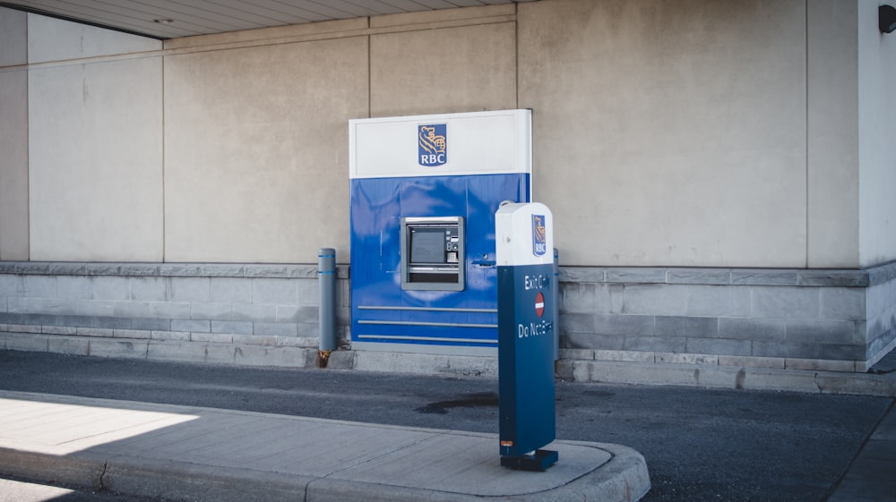 uma bomba de gasolina azul e branca ao lado de um edifício