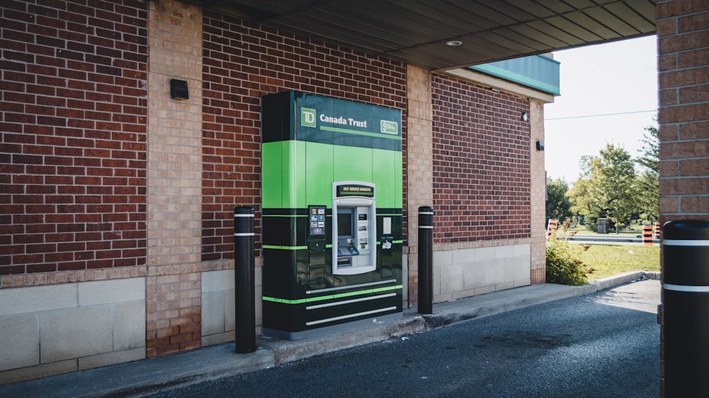 a green and black phone booth next to a brick building