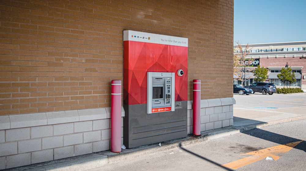 a red and gray machine next to a brick building